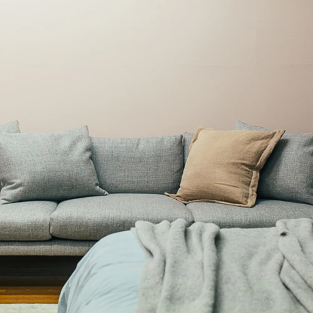Sofá gris azulado con almohadones y manta en un living luminoso