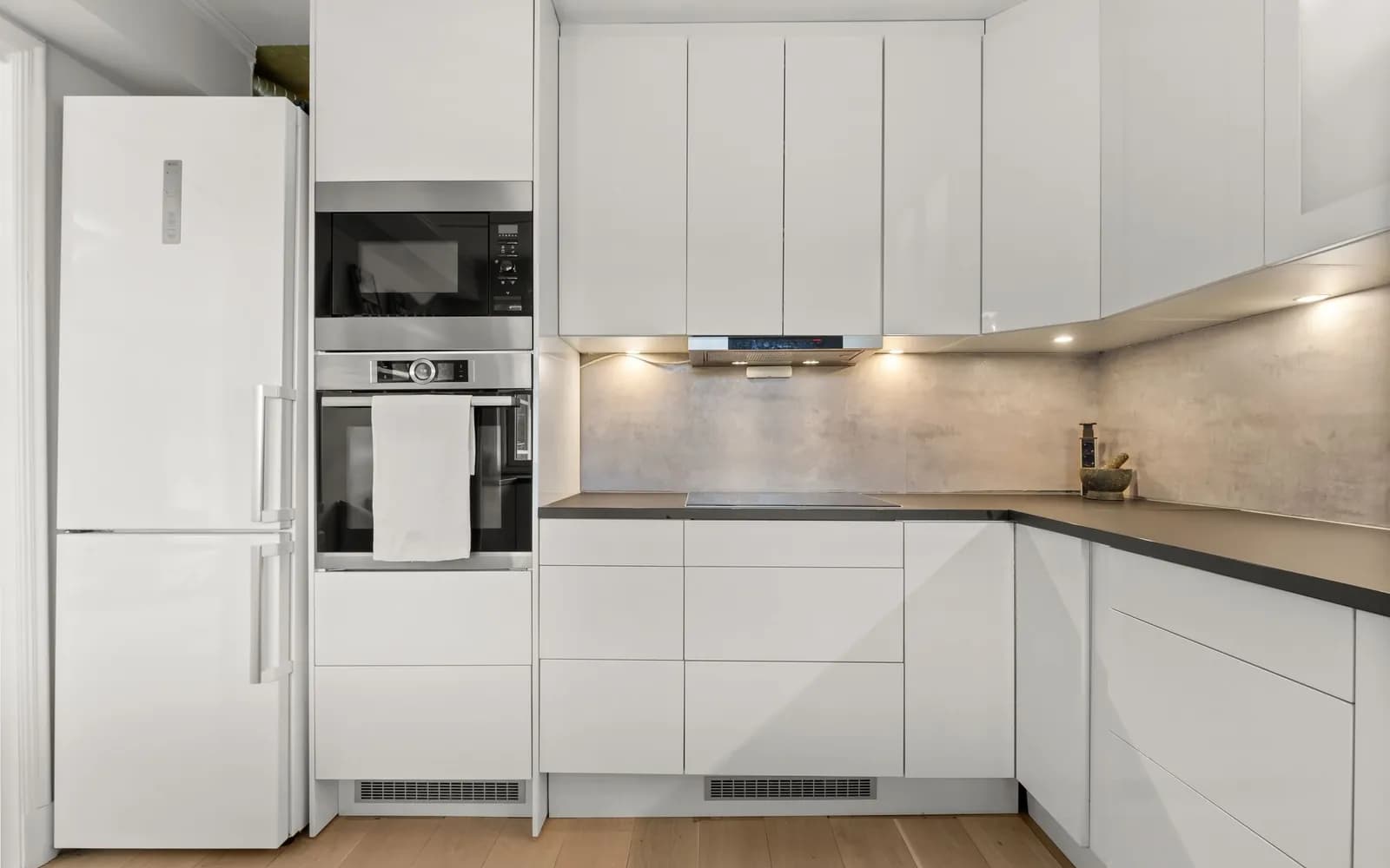 Cocina moderna y luminosa con heladera, microondas y horno empotrados, campana y encimera