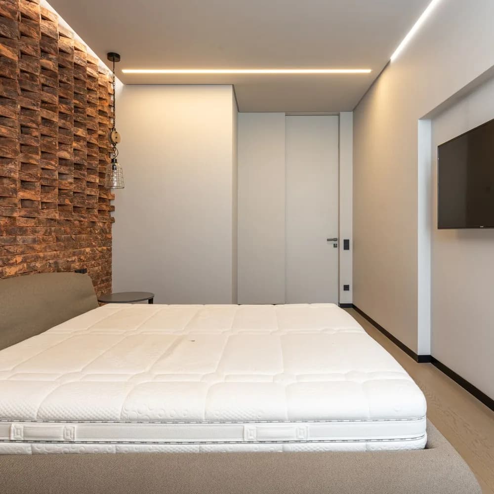Colchón King blanco de bordes reforzados en un dormitorio con pared de ladrillo